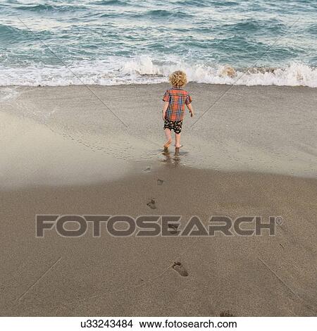 Picture - Rear view of little boy (2-3) walking on sandy beach. Fotosearch