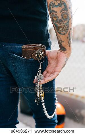 Stock Image - Rear view of man with keys in back pocket and skull tattoo, cropped. Fotosearch