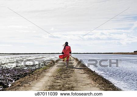 Rear view of young asian woman on dirt track by sea in traditional clothing, Tarragona, Catalonia, Spain View Large Photo Image Stock Photo - Rear view of young asian woman on dirt track by sea in traditional clothing, Tarragona, Catalonia, Spain. Fotosearch