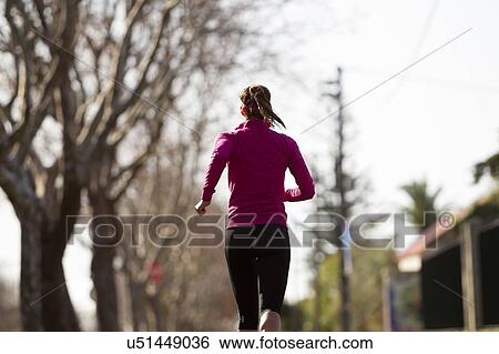 Stock Photograph - Rear view of young woman jogging. Fotosearch
