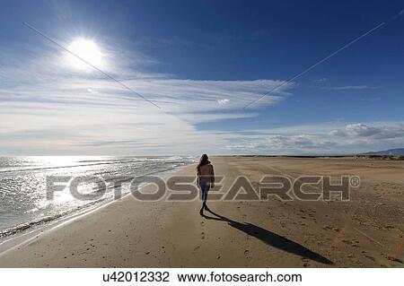 Rear view of young woman strolling along on beach, Tarragona, Catalonia, Spain View Large Photo Image Stock Image - Rear view of young woman strolling along on beach, Tarragona, Catalonia, Spain. Fotosearch