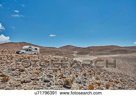 Stock Image - Recreational vehicle moving across landscape, Chiguana, Potosi, Bolivia, South America. Fotosearch