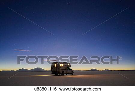 Stock Photograph - Recreational vehicle, travelling at dusk, across salt flats, Salar de Uyuni, Uyuni, Oruro, Bolivia, South America. Fotosearch