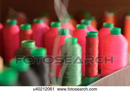 Stock Image - Red and green coloured threads in factory. Fotosearch