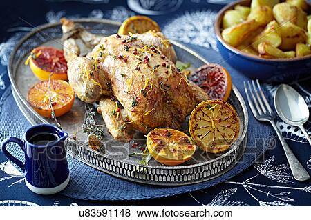 Stock Photo - Roast chicken with glazed citrus fruits on serving tray. Fotosearch