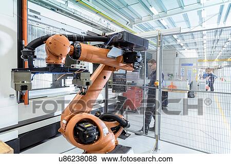 Stock Photo - Robotics engineer operating robot aided CNC machine in robotics research facility. Fotosearch