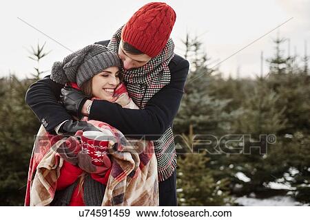 Romantic young couple in christmas tree forest wrapped in blanket View Large Photo Image Stock Photo - Romantic young couple in christmas tree forest wrapped in blanket. Fotosearch