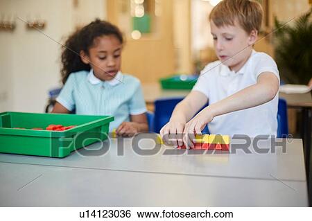 Stock Photograph - Schoolboy and girl constructing toy blocks in classroom at primary school. Fotosearch