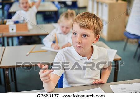 Stock Photo - Schoolboy counting with fingers in classroom at primary school. Fotosearch