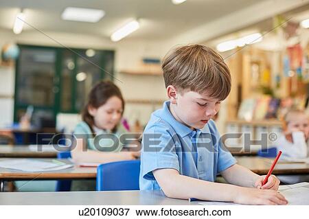 Stock Photo - Schoolboy counting writing in classroom lesson at primary school. Fotosearch