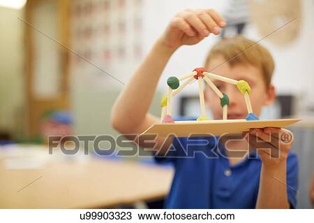 Stock Image - Schoolboy making ball and stick model in classroom at primary school. Fotosearch