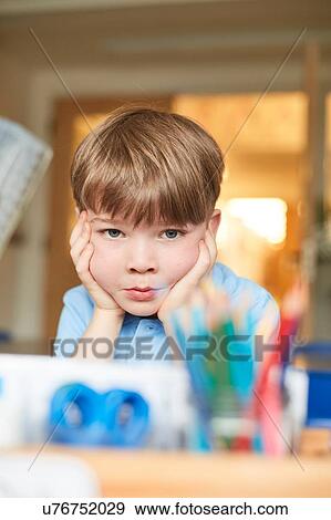 Schoolboy with chin on hands in classroom at primary school, portrait View Large Photo Image Stock Photo - Schoolboy with chin on hands in classroom at primary school, portrait. Fotosearch