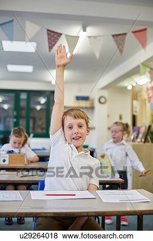 Schoolboy with hand up in classroom at primary school View Large Photo Image Stock Photo - Schoolboy with hand up in classroom at primary school. Fotosearch