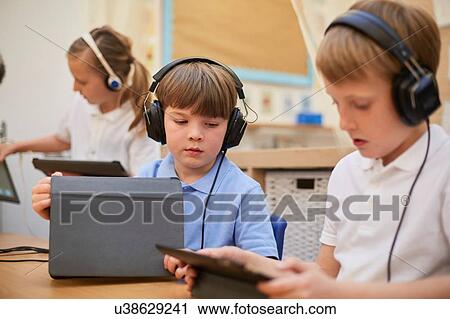 Schoolboys and girl listening to headphones in class at primary school View Large Photo Image Stock Image - Schoolboys and girl listening to headphones in class at primary school. Fotosearch