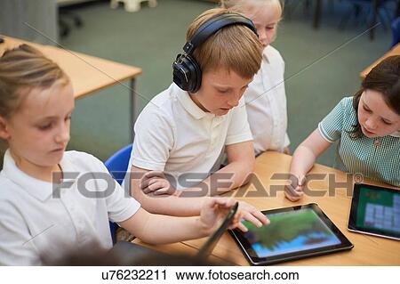 Schoolboys and girls looking at digital tablets in class at primary school View Large Photo Image Stock Image - Schoolboys and girls looking at digital tablets in class at primary school. Fotosearch