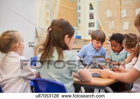 Stock Photo - Schoolboys and girls looking at digital tablets in class at primary school. Fotosearch