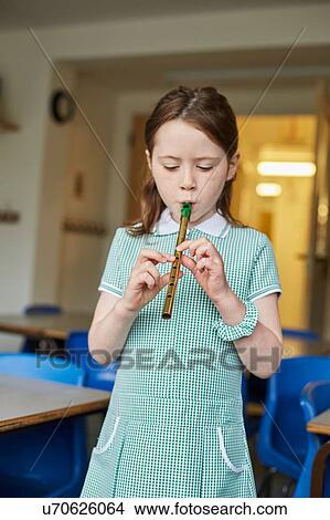 Picture - Schoolgirl playing recorder in classroom at primary school. Fotosearch