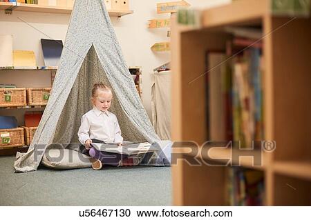 Schoolgirl sitting on floor reading in classroom at primary school View Large Photo Image Stock Image - Schoolgirl sitting on floor reading in classroom at primary school. Fotosearch