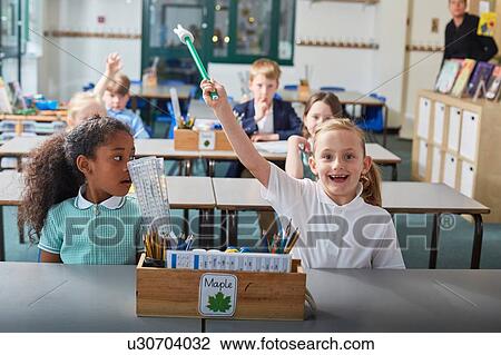 Schoolgirl with her hand raised in primary school classroom lesson View Large Photo Image Stock Image - Schoolgirl with her hand raised in primary school classroom lesson. Fotosearch