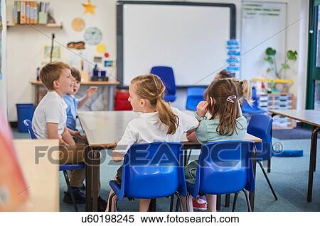 Stock Photography - Schoolgirls and boys around classroom table primary school. Fotosearch
