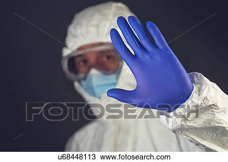 Stock Image - Scientist in protective clothing gesturing stop sign.. Fotosearch