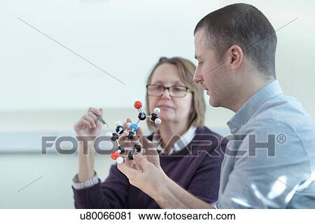 Stock Image - Scientists inspecting Ibuprofen model in meeting room. Fotosearch