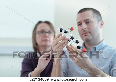 Stock Photo - Scientists inspecting Ibuprofen model in meeting room. Fotosearch