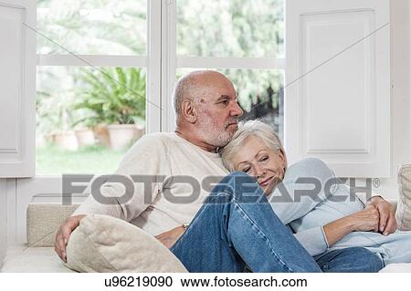 Stock Image - Senior couple relaxing together on sofa. Fotosearch