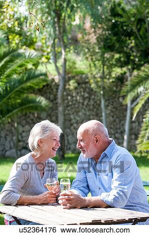 Senior couple sitting in garden, enjoying glass of wine View Large Photo Image Stock Photograph - Senior couple sitting in garden, enjoying glass of wine. Fotosearch
