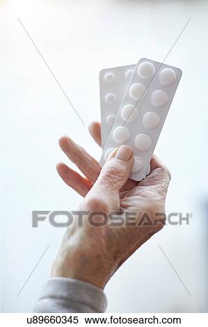 Stock Photography - Senior woman holding blister pack medication, close-up. Fotosearch