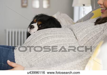 Stock Photograph - Side view of pregnant woman relaxing next to dog. Fotosearch