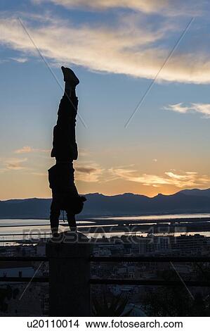 Silhouette of man doing handstand on railing, Cagliari, Sardinia, Italy View Large Photo Image Picture - Silhouette of man doing handstand on railing, Cagliari, Sardinia, Italy. Fotosearch