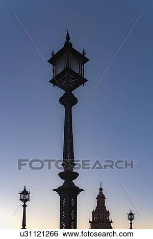Stock Photograph - Spain, Andalusia, Seville, Plaza de Espana, Old fashioned street lights against clear sky at dawn. Fotosearch