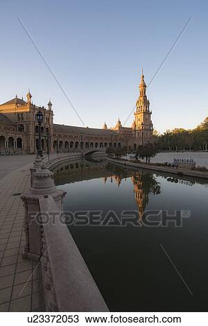 Stock Image - Spain, Andalusia, Seville, Tower in Plaza de Espana reflected in water. Fotosearch