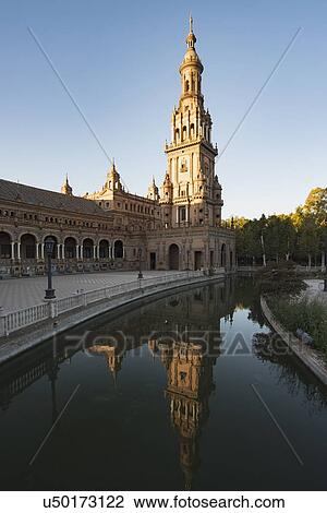Stock Image - Spain, Andalusia, Seville, Tower in Plaza de Espana reflected in water. Fotosearch