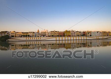 Stock Image - Spain, Seville, Colorful residential building reflecting in Guadalquivir river. Fotosearch