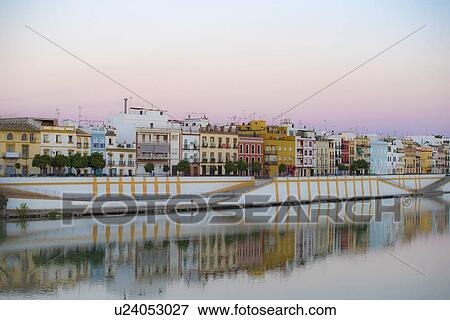 Stock Photo - Spain, Seville, Colorful residential building reflecting in Guadalquivir river. Fotosearch