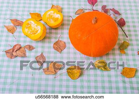 Stock Photo - Still life of pumpkin and chopped pumpkin with autumn leaves, close-up. Fotosearch