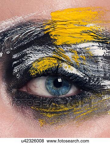 Stock Photo - Studio portrait of blue eyed woman with painted face, close up of eye. Fotosearch