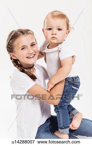 Studio portrait of kneeling girl holding baby brother View Large Photo Image Stock Photo - Studio portrait of kneeling girl holding baby brother. Fotosearch