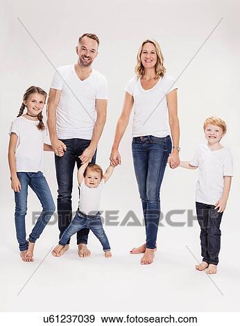 Stock Photo - Studio portrait of mature couple holding hands with daughter and sons, full length. Fotosearch
