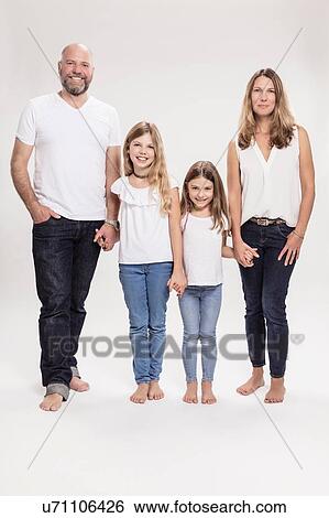 Stock Photograph - Studio portrait of mature couple with two daughters, full length. Fotosearch
