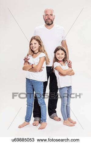 Stock Image - Studio portrait of mature man with two daughters, full length. Fotosearch