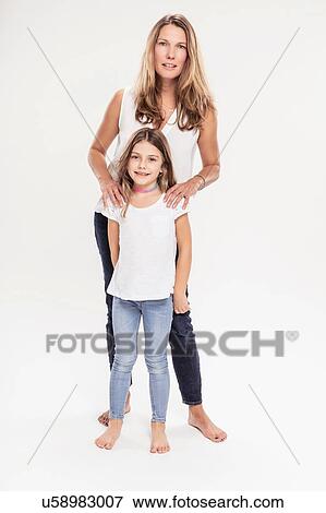 Stock Photo - Studio portrait of mature woman with daughter, full length. Fotosearch