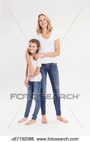 Stock Photograph - Studio portrait of mature woman with daughter, full length. Fotosearch