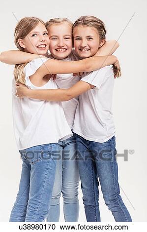 Stock Image - Studio portrait of three girls posing with arms around each other. Fotosearch