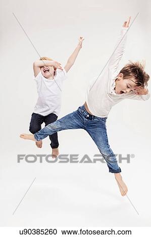 Studio portrait of two boys having fun jumping mid air, full length View Large Photo Image Stock Image - Studio portrait of two boys having fun jumping mid air, full length. Fotosearch