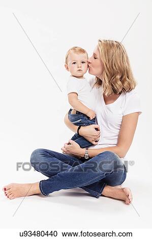 Studio portrait of woman sitting cross legged on floor kissing baby son View Large Photo Image Stock Image - Studio portrait of woman sitting cross legged on floor kissing baby son. Fotosearch