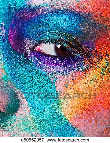Stock Photo - Studio portrait of young woman's face with multi coloured powder eye shadow, close up. Fotosearch