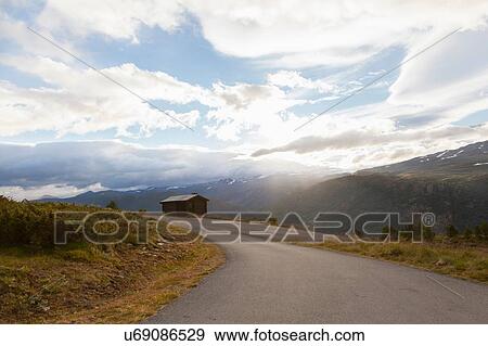 Stock Photo - Sunlit rural road in mountain landscape, Jotunheimen National Park, Lom, Oppland, Norway. Fotosearch
